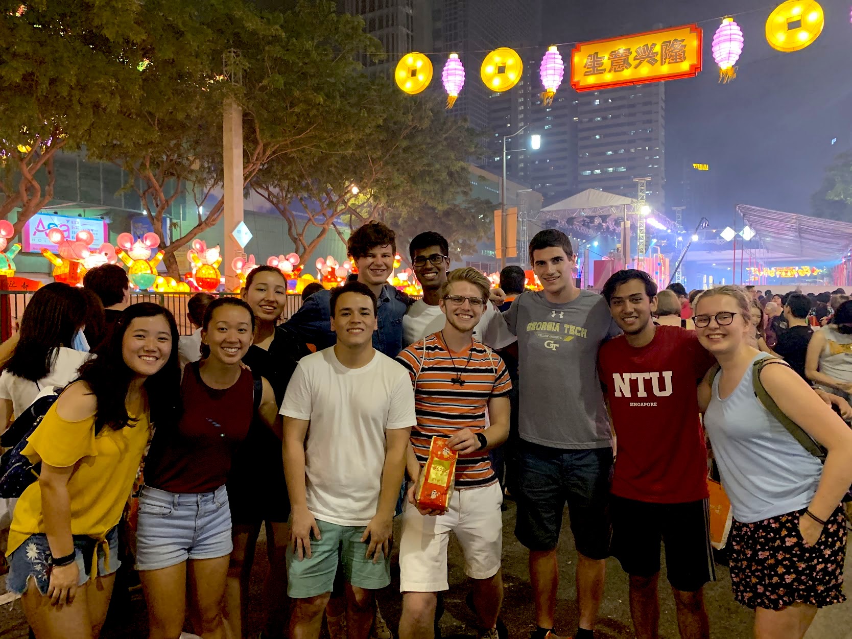 Group of 10 Tech students posing for a photo in a crowded, colorful square in Singapore
