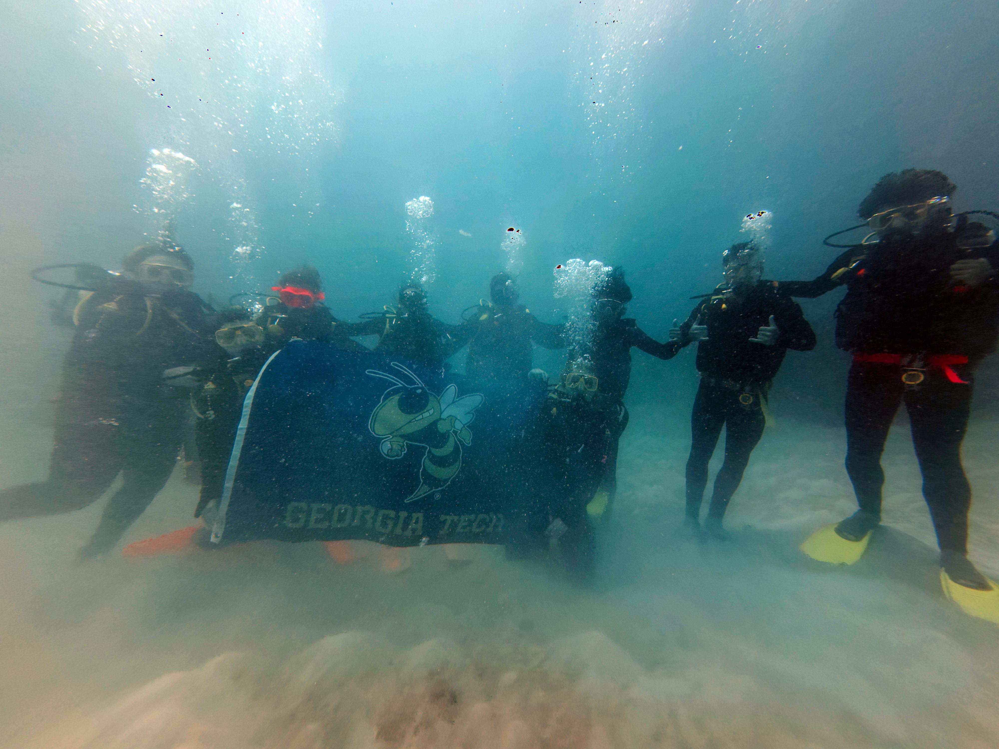 Students scuba diving with Georgia Tech flag.