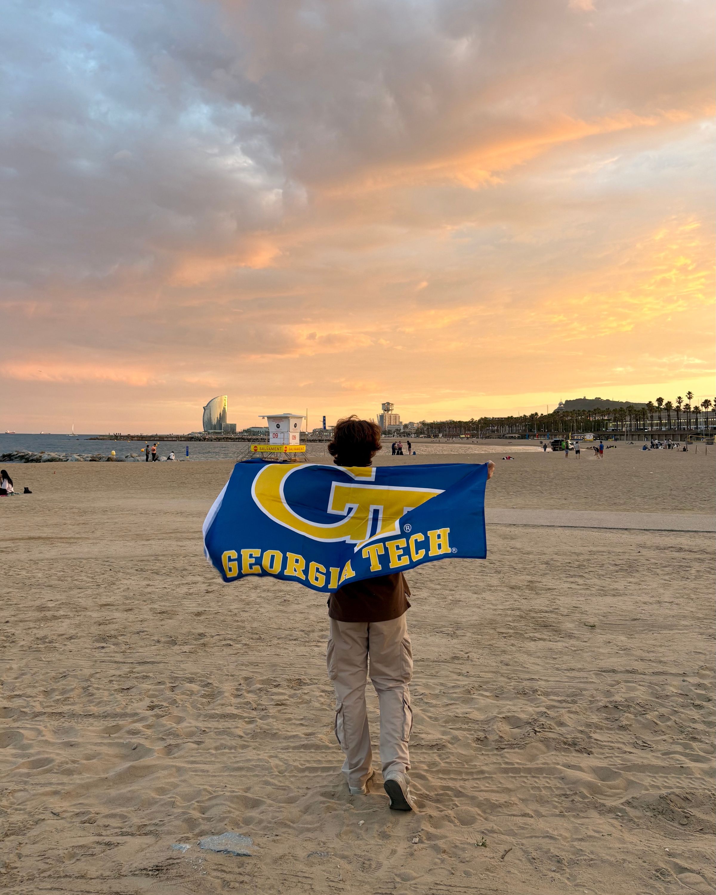Student running on the beach in Barcelona flying the Georgia Tech flag.